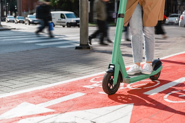 Mulher a andar de scooter ao longo da estrada da pista de bicicletas na cidade