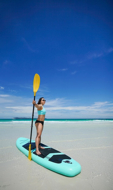 Mulher a bordo de sup ou prancha de remo na praia