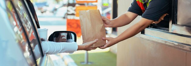 Foto mulher a comer fast food no drivethru.