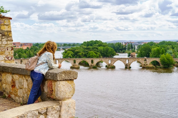 Mulher a espreitar o rio que passa em frente à cidade medieval de Zamora