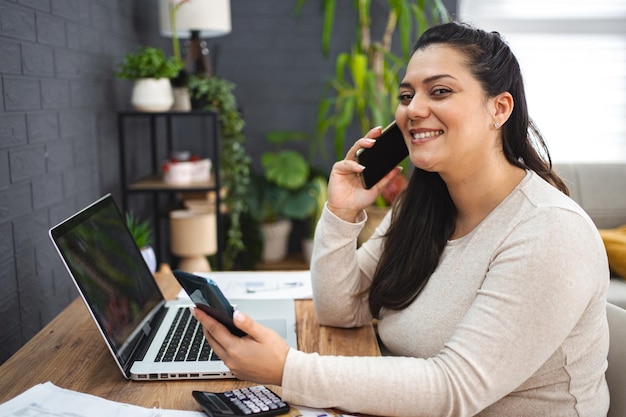 Mulher a falar ao telefone enquanto faz as finanças da casa.