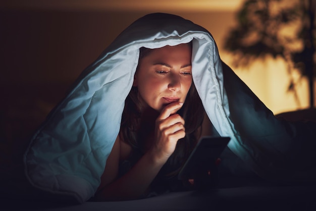 Mulher à noite na cama com telefone