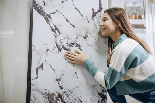 Mulher à procura de azulejos no mercado de construção