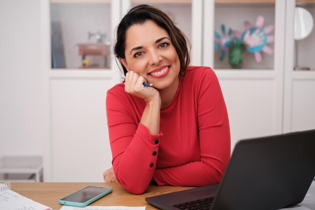 Foto mulher a trabalhar na sua secretária de casa ligada ao computador na reunião conceito de teletrabalho