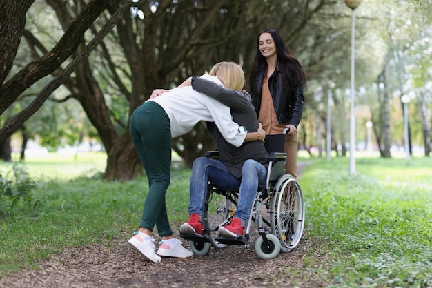 Mulher abraça homem em cadeira de rodas no parque de apoio e reabilitação do conceito de pessoas