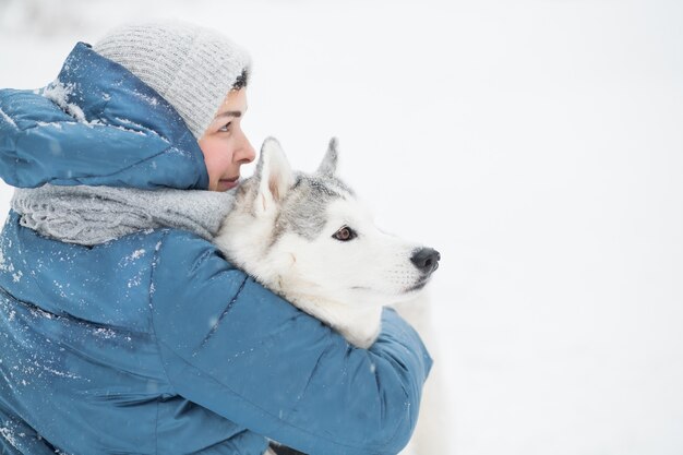 Mulher abraçando o husky siberiano nevado no inverno. feche o retrato. Cachorro. Foto de alta qualidade