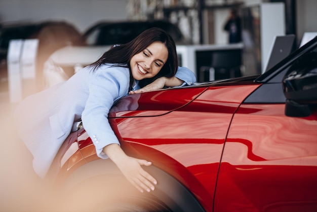 Mulher abraçando seu novo carro vermelho