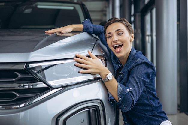 Foto mulher abraçando um carro novo em um showroom de carros