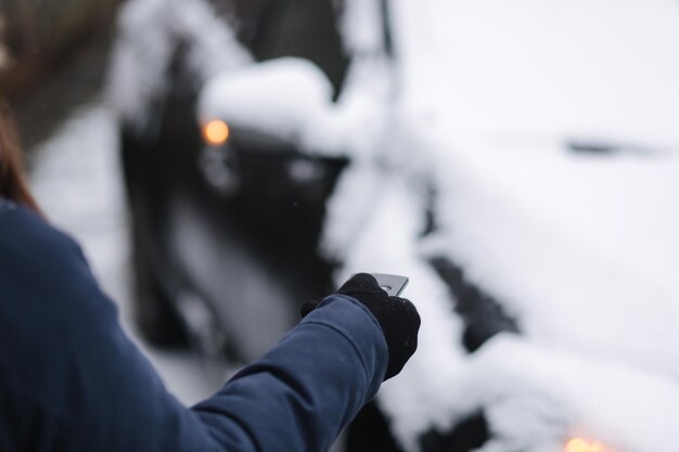 Mulher abre carro usando controle remoto em close de mulher segura chave do carro inverno ao ar livre