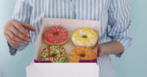 Mulher abre uma caixa de pães e come donuts saborosos