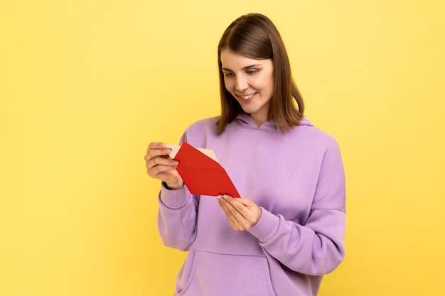 Mulher abrindo envelope e lendo carta com expressão positiva recebeu notícias agradáveis inesperadas