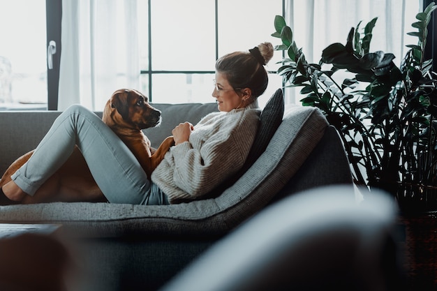 Mulher acariciando, brincando com seu cachorro em casa