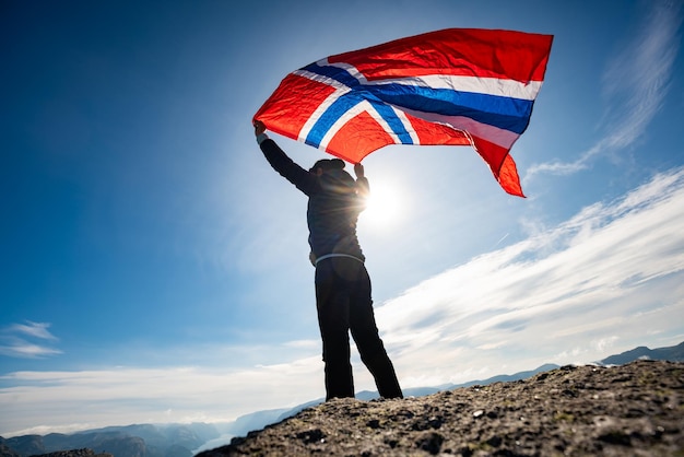 Mulher acenando com uma bandeira da noruega no fundo da natureza