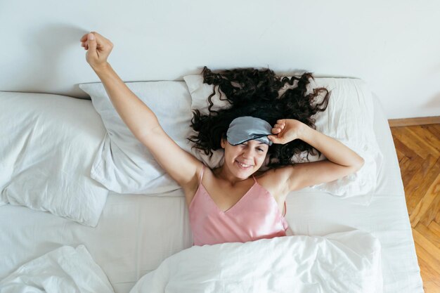 Mulher acordando com a máscara de dormir da manhã brilhante