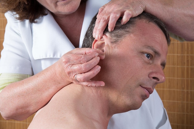 Foto mulher acupunturista se prepara para tocar agulha em torno das orelhas do homem