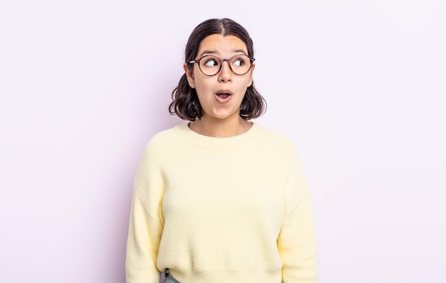 Mulher adolescente bonita se sentindo chocada, feliz, maravilhada e surpresa, olhando para o lado com a boca aberta
