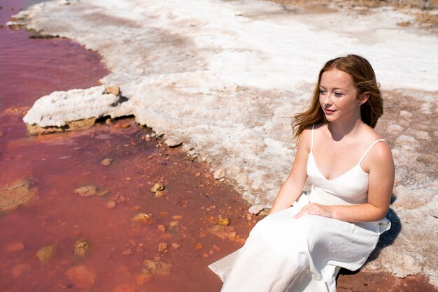 Mulher adolescente bonito vestido branco, sentado em um lago rosa incrível