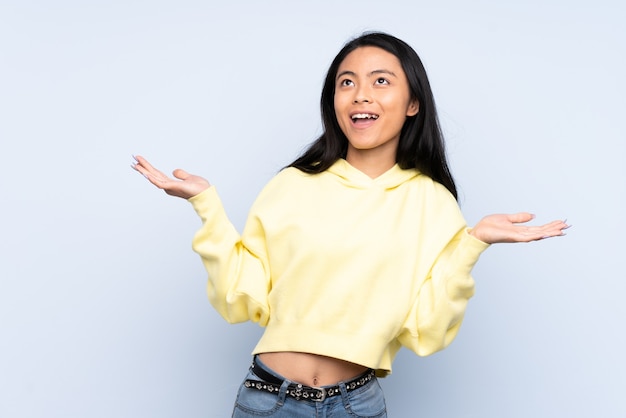 Mulher adolescente chinesa isolada no azul sorrindo muito