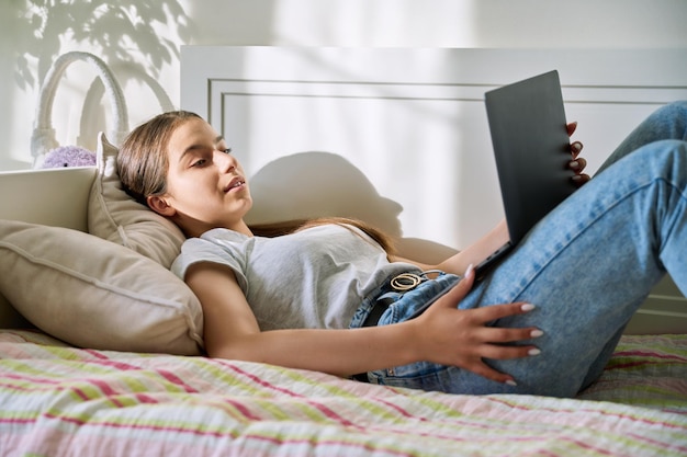 Mulher adolescente deitada no sofá em casa usando laptop para videochamada de bate-papo em conferência