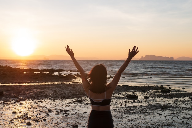 Mulher adolescente em biquíni. A mulher relaxa na praia no feriado do pôr do sol para um conceito de estilo de vida de felicidade