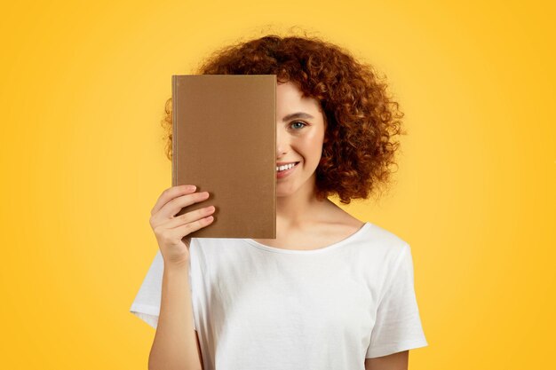 Foto mulher adolescente europeia segura livro sobre fundo amarelo