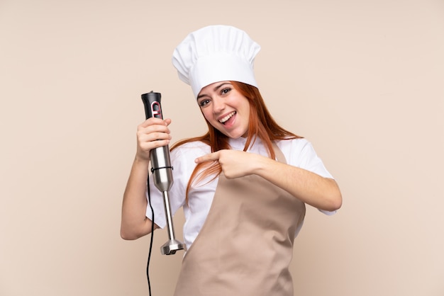 Mulher adolescente ruiva usando liquidificador e apontando-o