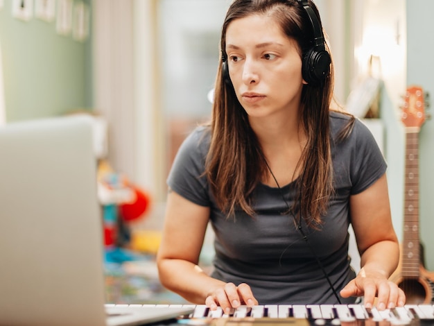 Mulher adulta a tocar piano sentada em casa.