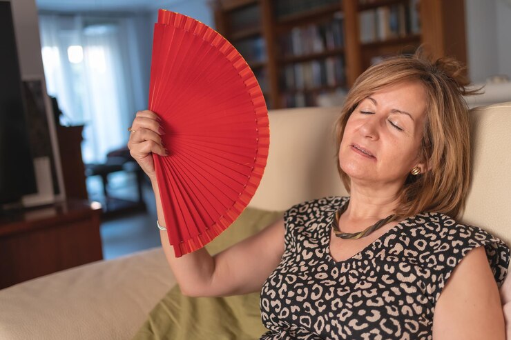 Mulher adulta abanada pelo alto calor produzido pela menopausa e distúrbio hormonal