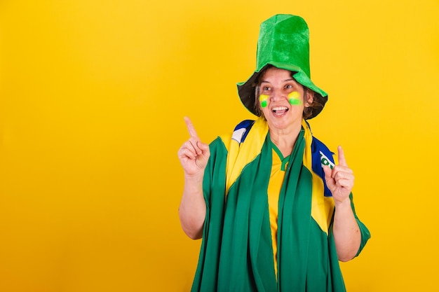 Mulher adulta adulta fã de futebol brasileiro vestindo bandeira e chapéu dançando festejando