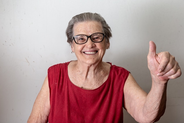 Mulher adulta bonita com dois tumbs acima. sênior caucasiano alegre que mostra dois polegares acima no fundo branco.