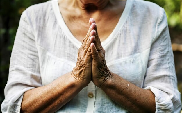 Mulher adulta com as mãos segurando a cruz orando por Deus Religião