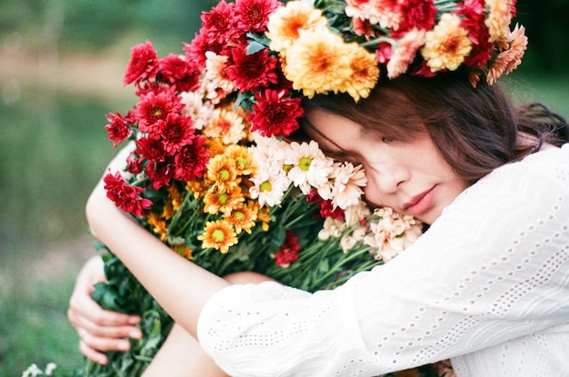 Mulher adulta com flores coloridas a dormir na floresta