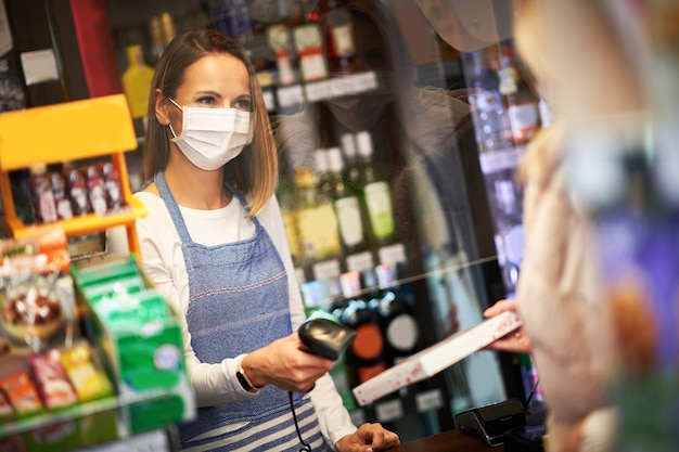mulher adulta com máscara médica comprando mantimentos