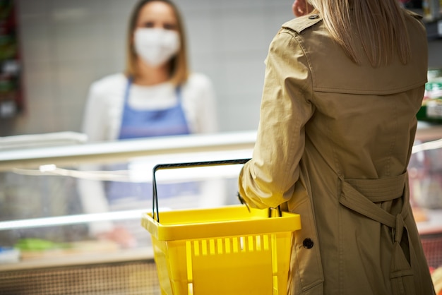 mulher adulta com máscara médica comprando mantimentos