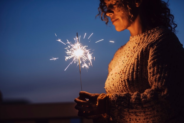 Mulher adulta com os olhos fechados segurando um diamante à noite com o céu azul ao fundo