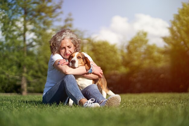 Mulher adulta com seu cachorro Beagle sentado na grama em um parque público