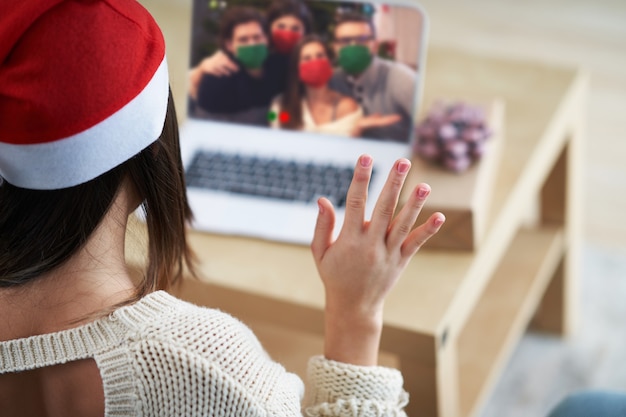 mulher adulta comemorando o Natal em casa e fazendo videochamada com amigos