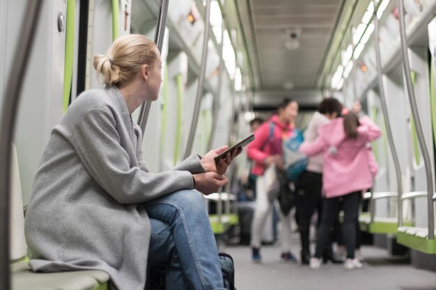 Mulher adulta em meio a olhar para longe enquanto está sentada no metrô