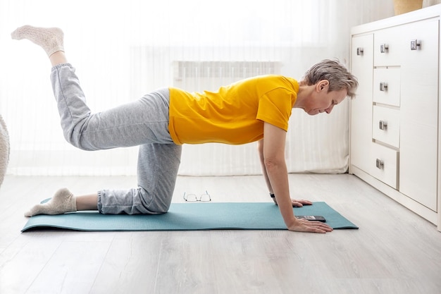 Mulher adulta faz fitness em casa