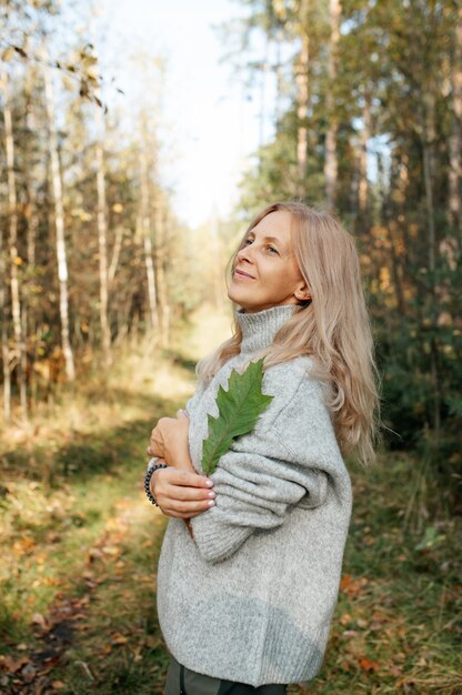 Mulher adulta feliz na floresta de outono