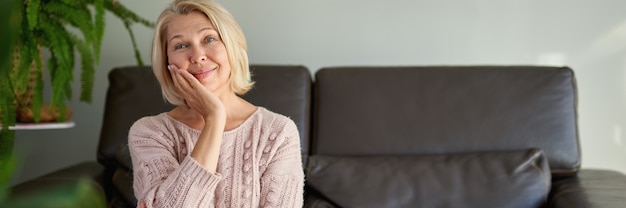 Mulher adulta feliz sentada no sofá