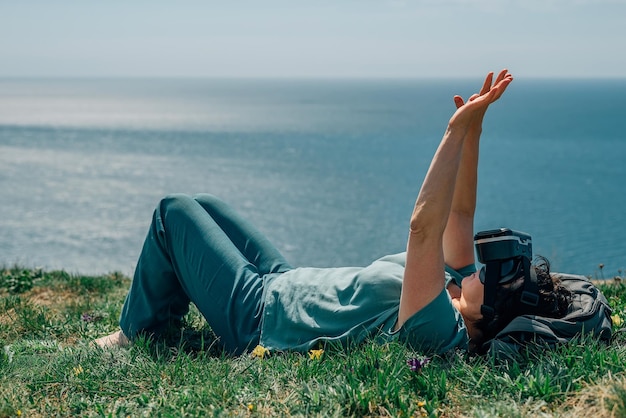 Mulher adulta fica na montanha contra o fundo do mar no verão primavera óculos de realidade virtual vr