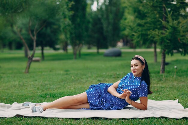 Mulher adulta jovem bonita no vestido azul piquenique no prado no parque.