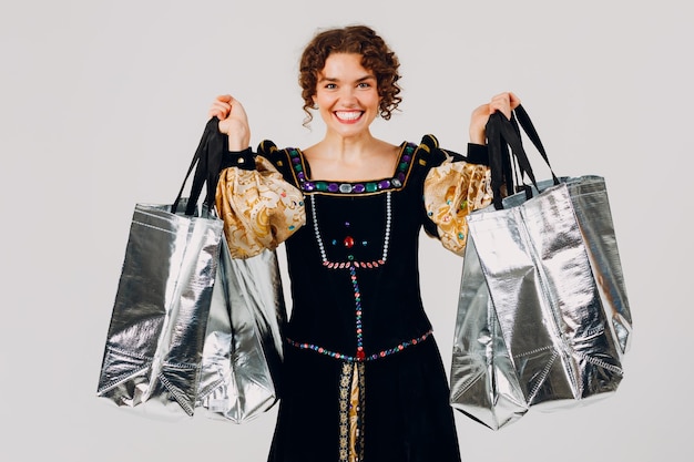 Foto mulher adulta jovem vestida com um vestido medieval segurando sacos de compras nas mãos isolado fundo branco