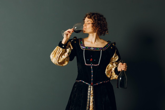 Mulher adulta jovem vestida com um vestido medieval segurando um copo de vinho