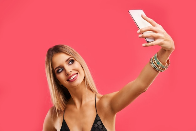 Foto mulher adulta linda loira posando rosa com smartphone