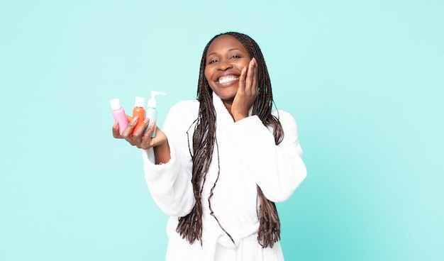 Mulher adulta negra afro-americana de roupão e segurando produtos cosméticos