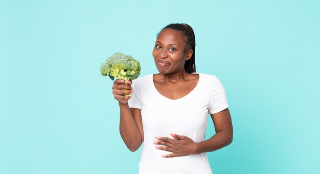 Mulher adulta negra afro-americana segurando um brócolis