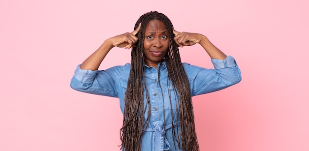 Mulher adulta negra negra com um olhar sério e concentrado, fazendo um brainstorming e pensando sobre um problema desafiador