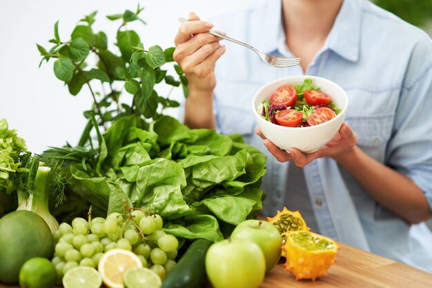 mulher adulta saudável com comida verde na cozinha